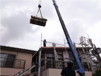 クレーンで資材を屋根の上に運ぶ